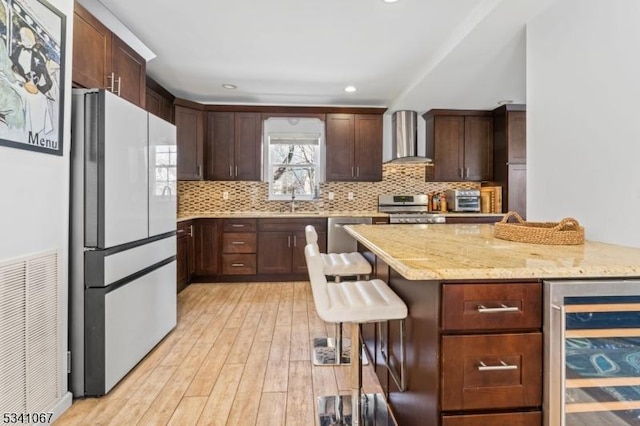 kitchen with wine cooler, visible vents, light wood-style floors, appliances with stainless steel finishes, and wall chimney range hood