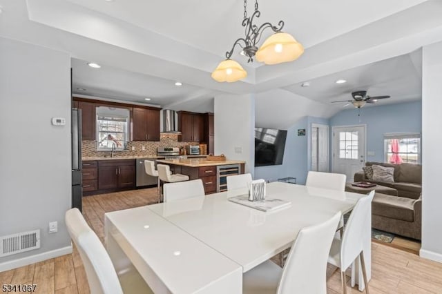 dining space featuring light wood-type flooring, wine cooler, plenty of natural light, and visible vents