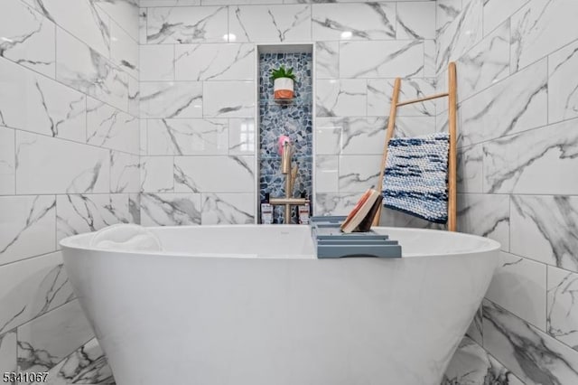 bathroom featuring stone wall, a freestanding tub, and tile walls