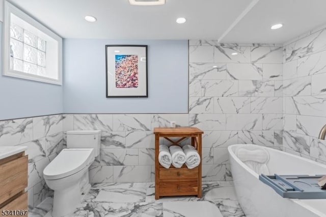 full bathroom featuring toilet, a soaking tub, vanity, and recessed lighting