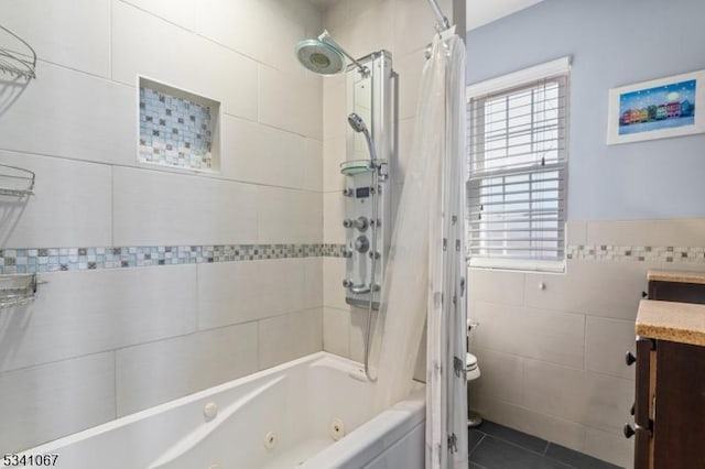 bathroom featuring tile walls, a combined bath / shower with jetted tub, toilet, vanity, and tile patterned floors