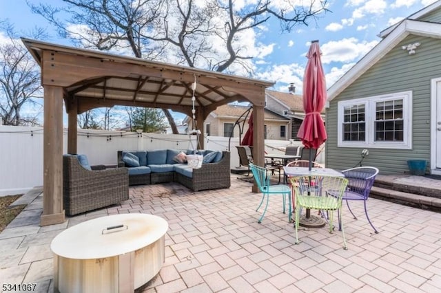 view of patio with outdoor dining space, fence, a gazebo, and an outdoor hangout area