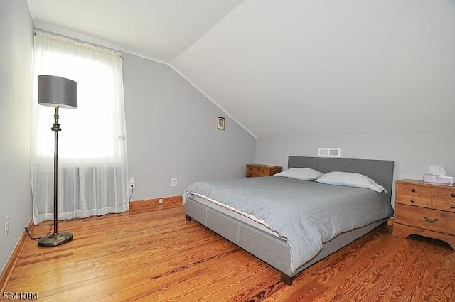 bedroom featuring baseboards, vaulted ceiling, and wood finished floors