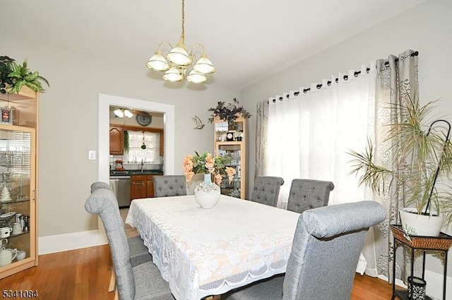 dining area with a chandelier, plenty of natural light, and wood finished floors