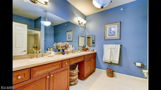 bathroom featuring a sink, a shower stall, baseboards, and double vanity