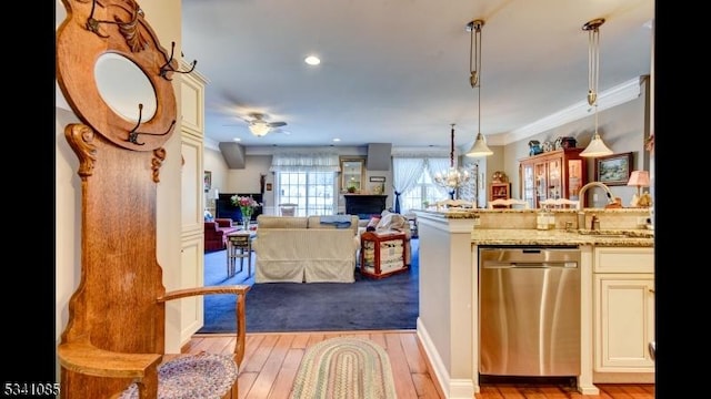 kitchen featuring decorative light fixtures, light stone countertops, cream cabinetry, light wood-style floors, and stainless steel dishwasher