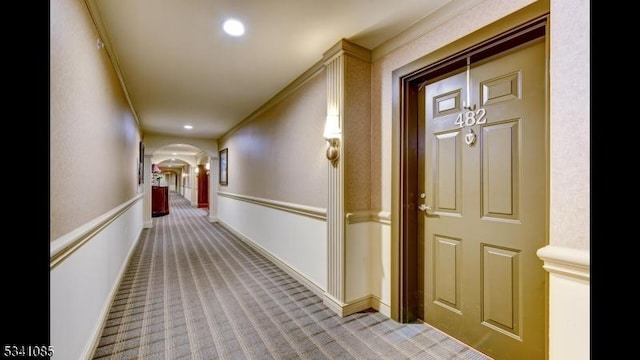 corridor with arched walkways, ornamental molding, recessed lighting, and light colored carpet