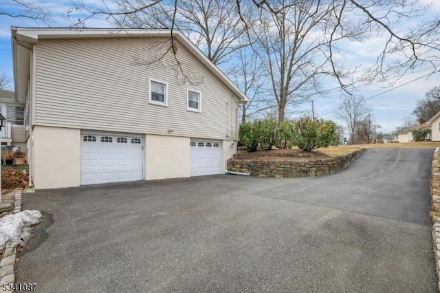 view of property exterior featuring driveway, an attached garage, and stucco siding