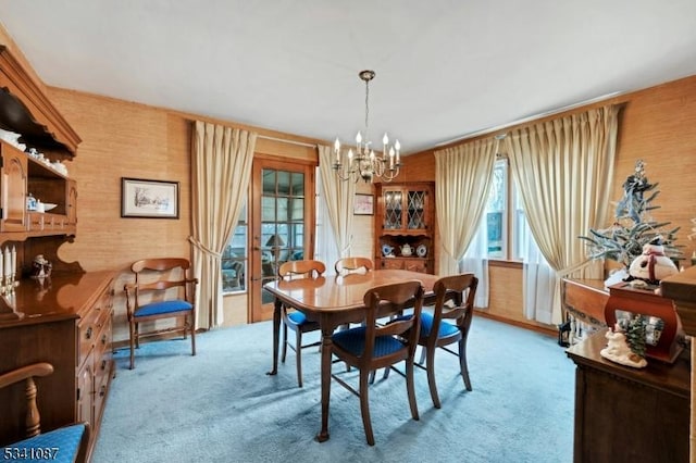 dining space with light colored carpet and a notable chandelier