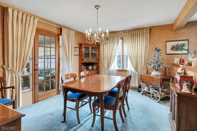 dining room with carpet floors, beamed ceiling, and an inviting chandelier