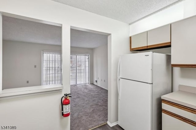 kitchen with dark carpet, light countertops, a textured ceiling, and freestanding refrigerator