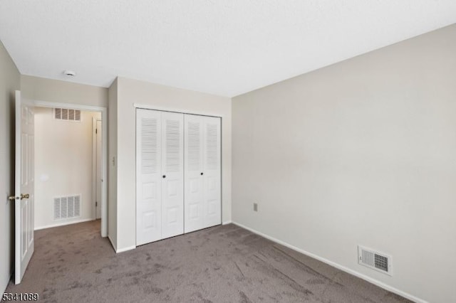 unfurnished bedroom with carpet, visible vents, and a closet