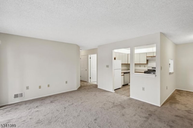 unfurnished living room featuring a textured ceiling, baseboards, visible vents, and light colored carpet