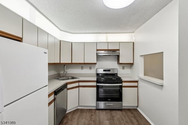 kitchen with under cabinet range hood, dark wood-type flooring, a sink, light countertops, and appliances with stainless steel finishes