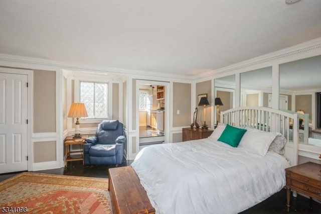 bedroom featuring crown molding, a decorative wall, and wood finished floors