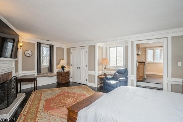 bedroom featuring baseboards, ornamental molding, a fireplace with raised hearth, and wood finished floors