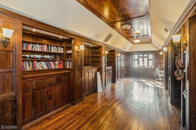 interior space featuring vaulted ceiling, built in shelves, dark wood-type flooring, and visible vents