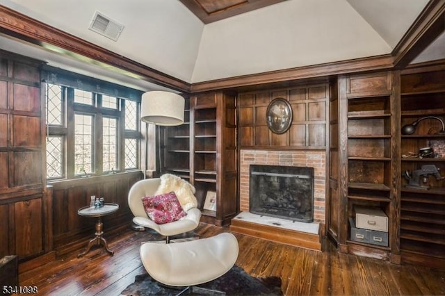 living area with lofted ceiling, a brick fireplace, visible vents, and dark wood finished floors