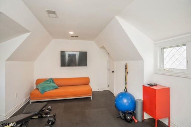 exercise room featuring visible vents, vaulted ceiling, and baseboards