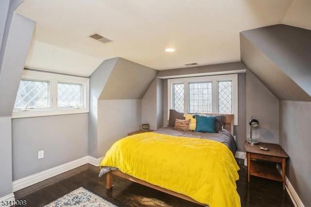 bedroom featuring lofted ceiling, visible vents, baseboards, and wood finished floors