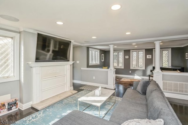 living room featuring baseboards, crown molding, ornate columns, and wood finished floors