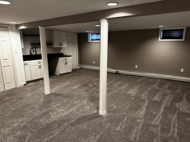 finished basement with a sink, baseboards, and dark carpet