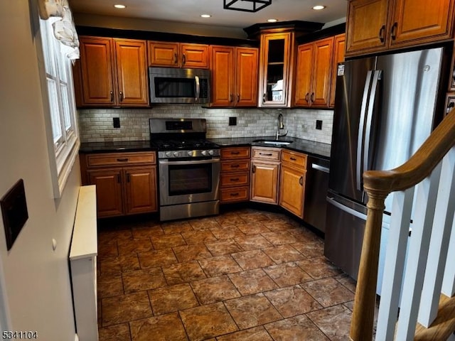 kitchen featuring decorative backsplash, dark countertops, appliances with stainless steel finishes, and a sink