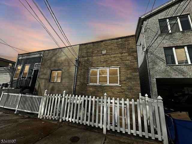 exterior space featuring stone siding and a fenced front yard