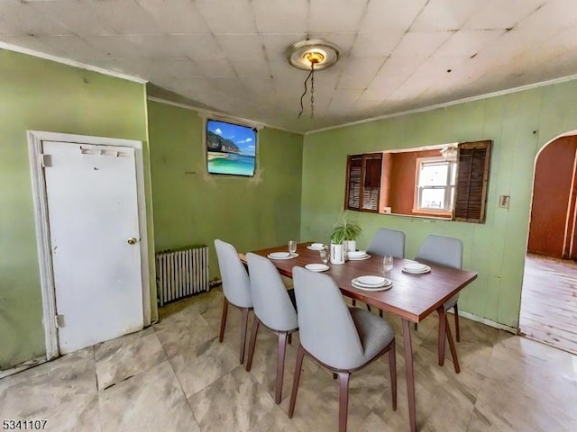 dining room with radiator heating unit, arched walkways, and crown molding