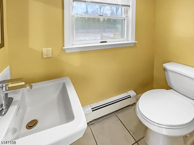 half bathroom featuring a baseboard heating unit, a sink, toilet, and tile patterned floors