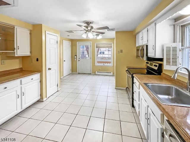 kitchen featuring white cabinets, appliances with stainless steel finishes, baseboard heating, a sink, and light tile patterned flooring