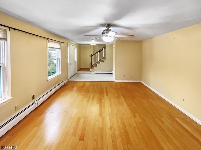 unfurnished living room featuring a baseboard radiator, light wood-style flooring, baseboard heating, baseboards, and stairs