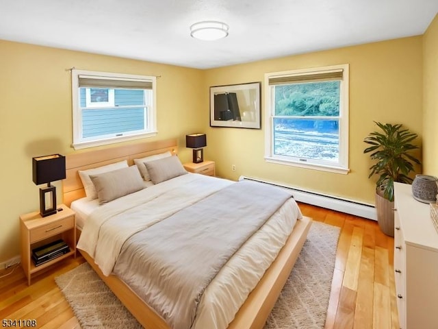 bedroom featuring light wood-type flooring and a baseboard radiator