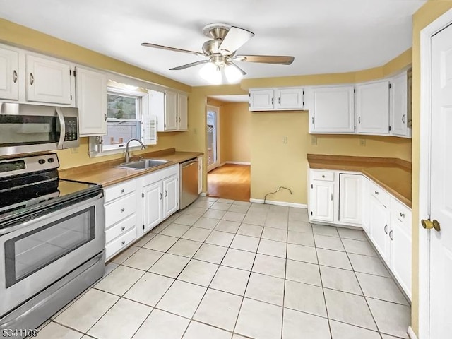 kitchen featuring light tile patterned floors, white cabinetry, stainless steel appliances, and a sink