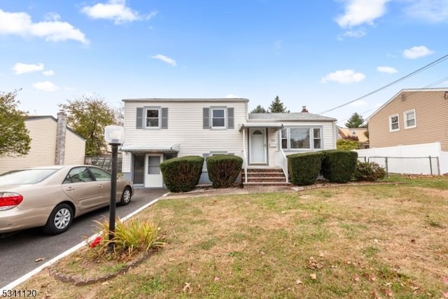 tri-level home featuring fence and a front lawn