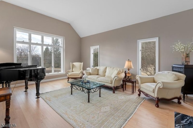 living area featuring baseboards, vaulted ceiling, and wood finished floors