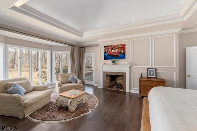 interior space with a decorative wall, a fireplace, wood finished floors, ornamental molding, and a tray ceiling