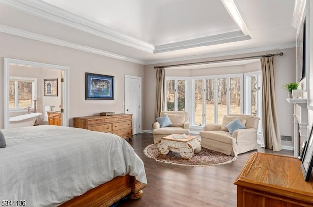 bedroom with a tray ceiling, dark wood finished floors, connected bathroom, and ornamental molding