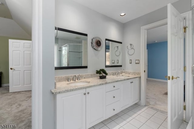 bathroom featuring double vanity, a stall shower, a sink, and tile patterned floors