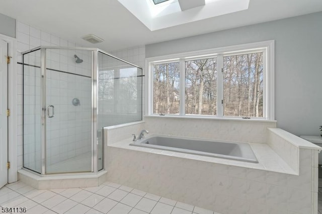 bathroom featuring a skylight, tile patterned flooring, a garden tub, and a stall shower