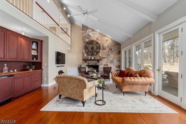 living area featuring dark wood finished floors, ceiling fan, beamed ceiling, a fireplace, and high vaulted ceiling