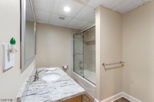 bathroom featuring enclosed tub / shower combo, a drop ceiling, vanity, visible vents, and baseboards