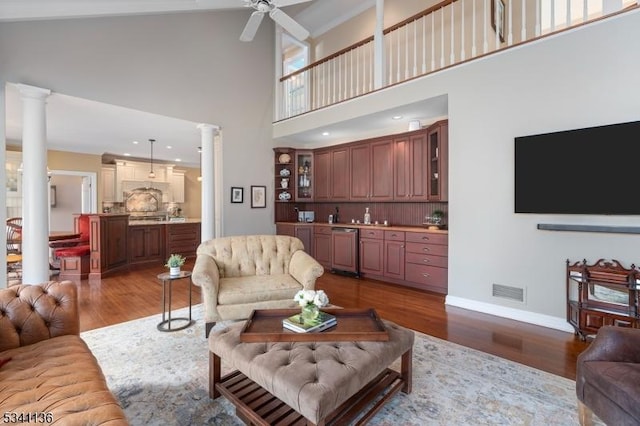 living room featuring decorative columns, visible vents, ceiling fan, wood finished floors, and baseboards