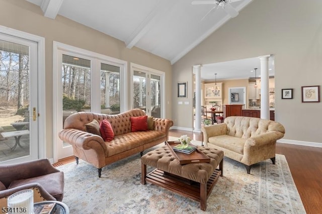 sunroom / solarium with vaulted ceiling with beams, a wealth of natural light, decorative columns, and a ceiling fan