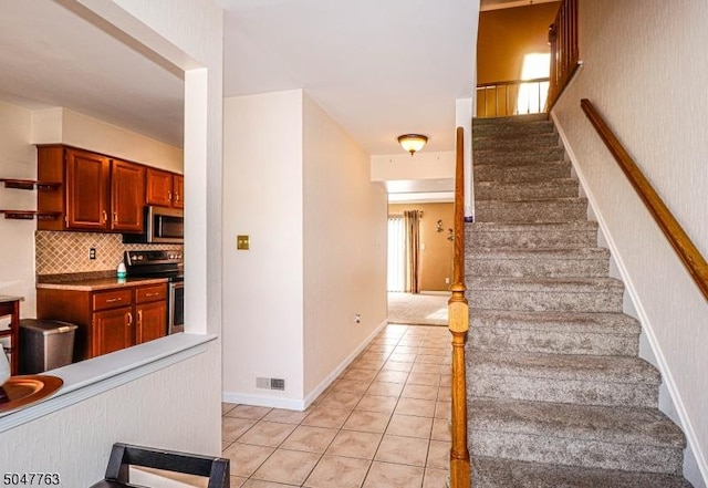 stairway featuring tile patterned flooring, visible vents, and baseboards