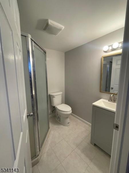 full bathroom with toilet, a stall shower, tile patterned floors, and vanity