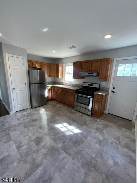 kitchen with recessed lighting, under cabinet range hood, stainless steel appliances, light countertops, and brown cabinetry