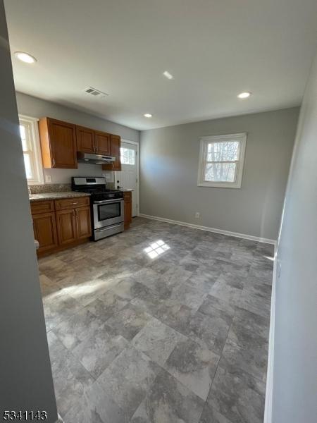 kitchen featuring stainless steel gas stove, under cabinet range hood, baseboards, and visible vents