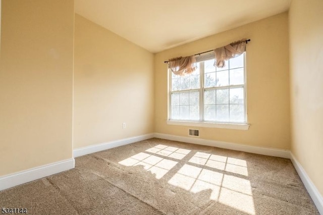 carpeted empty room featuring visible vents, baseboards, and vaulted ceiling