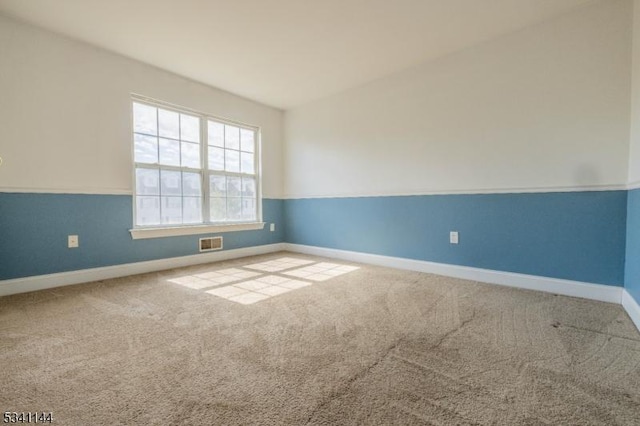 carpeted spare room featuring visible vents and baseboards